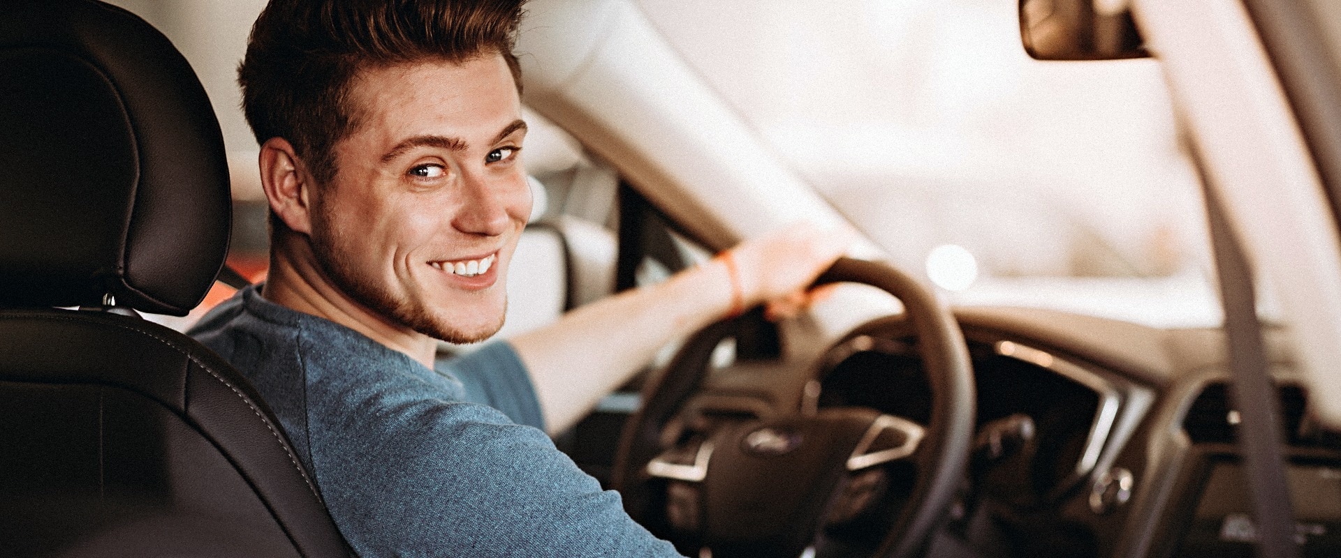 Happy young driver behind the wheel of a car. Buying a car and driving concept.